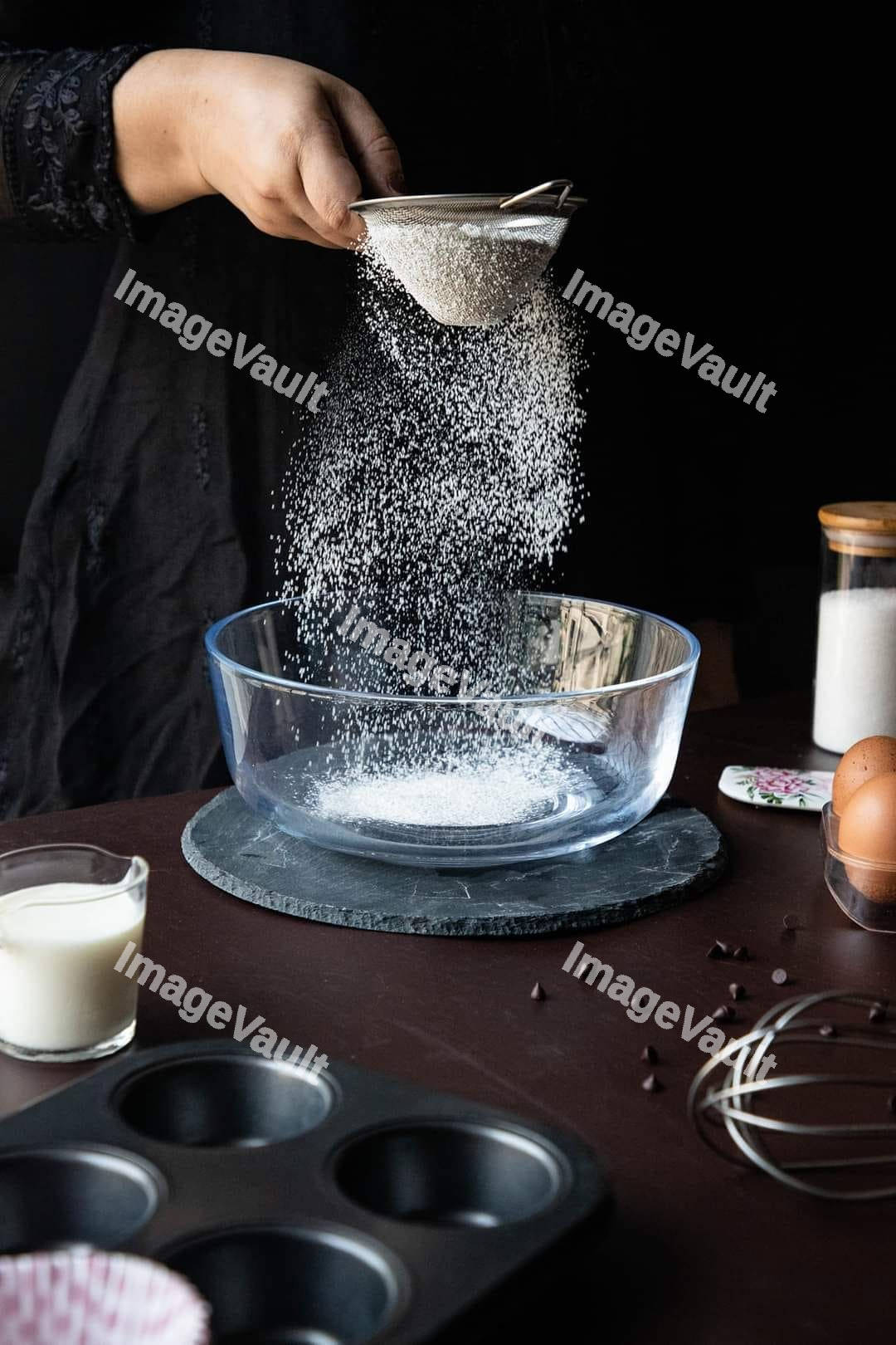 Hand pouring sugar into a bowl